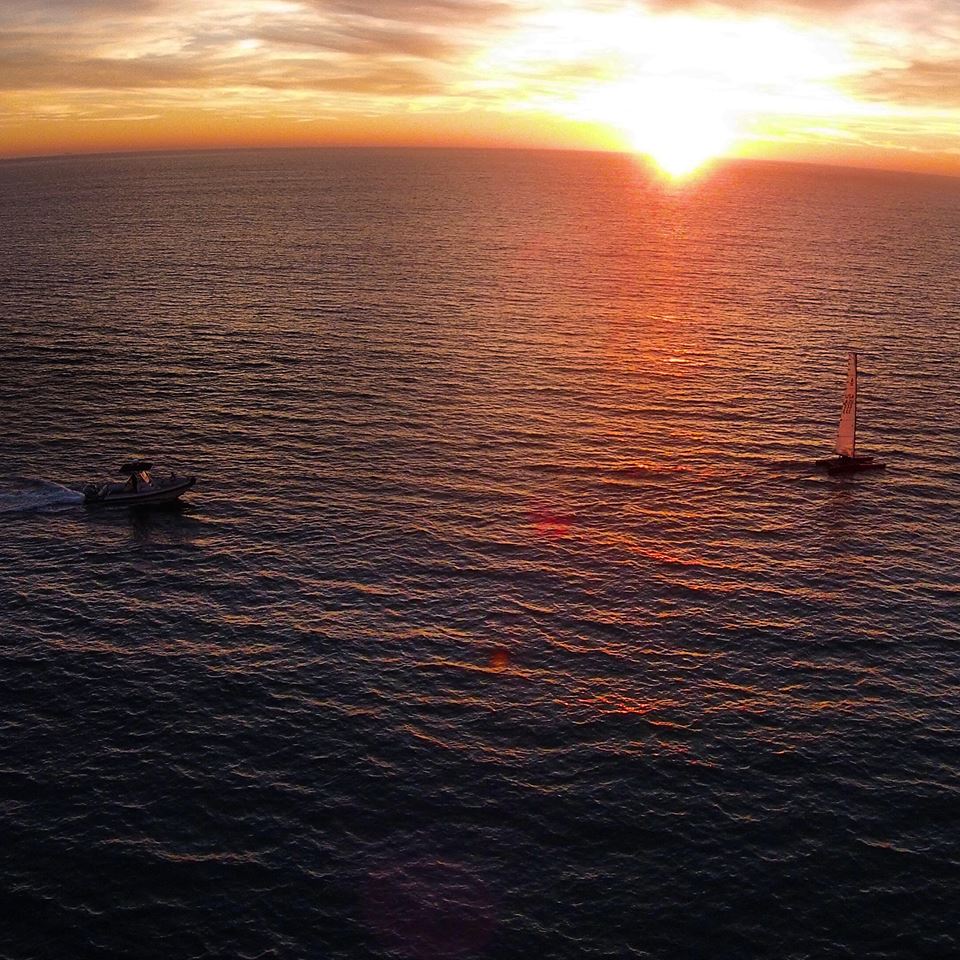 Philippe Kahn sailing the A-Cat. Photo was taken with a drone, and shows the chase boat in the light air and sunset.